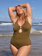 Blonde model wears flattering cut out halter neck one piece in khaki textured fabric