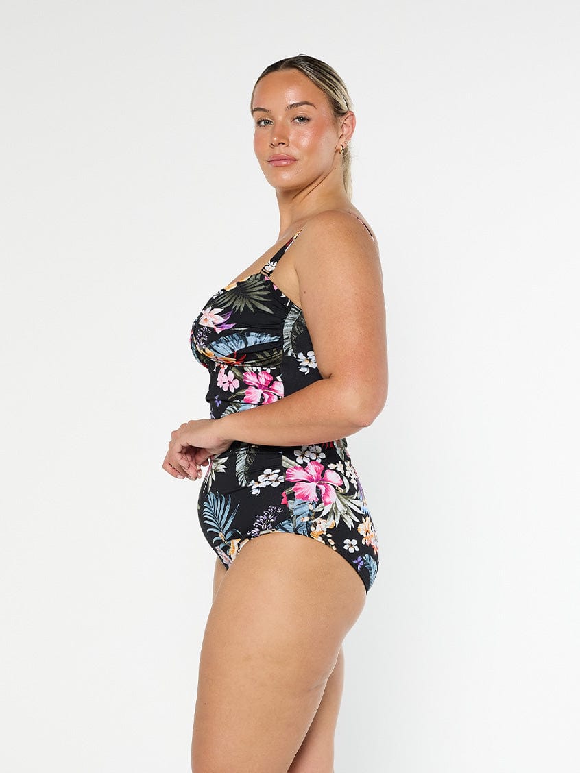 Blonde model wears black floral one piece in pool proof fabric with removable straps