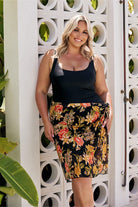 Model at beach wearing black floral mesh wrap beach skirt