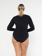 Blonde model shows the back of black chlorine resistant long sleeve one piece with full coverage bottom