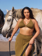 Brunette model wears full length olive beach skirt with ring detail and full side split