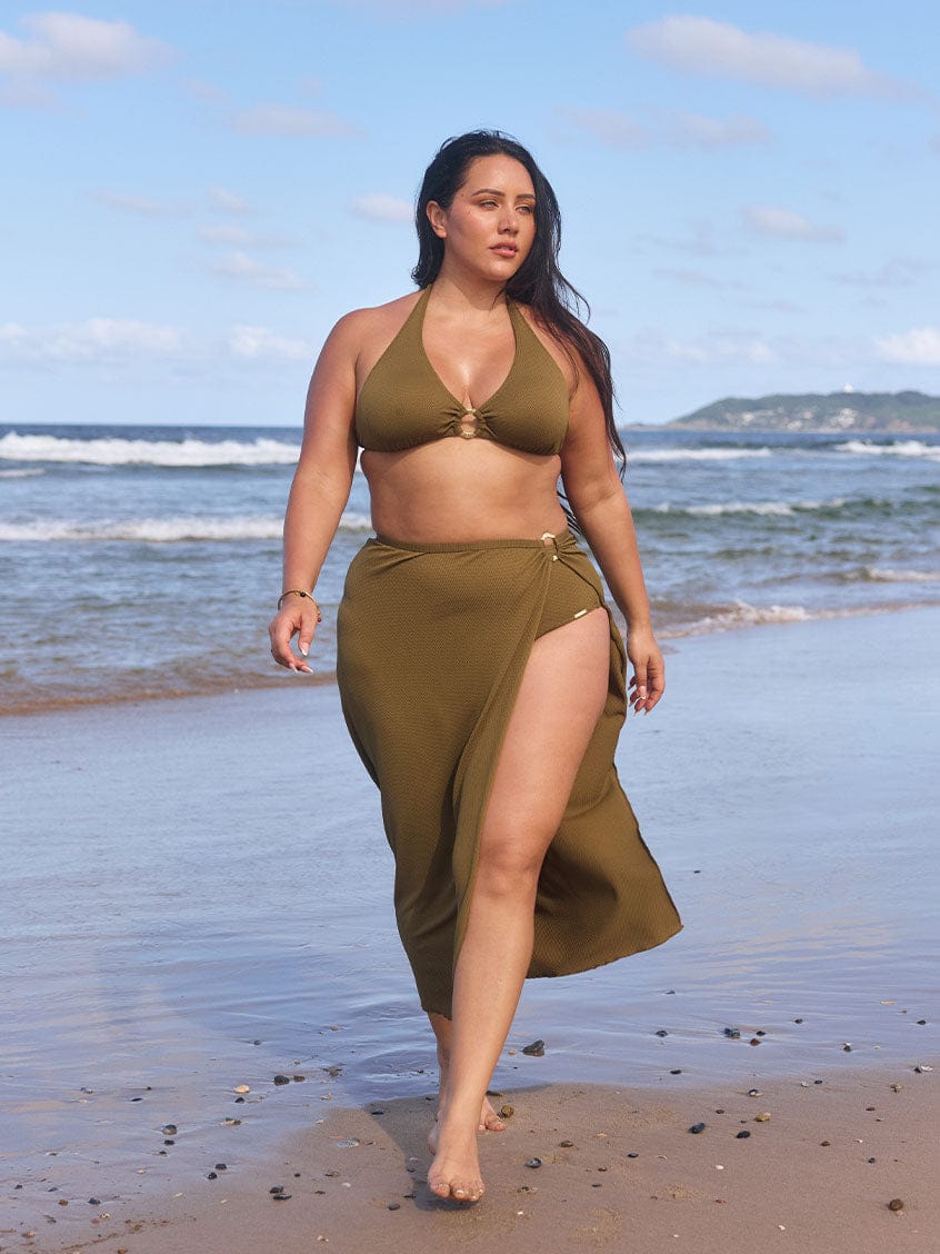Model walks on beach wearing olive full length skirt with flattering side split