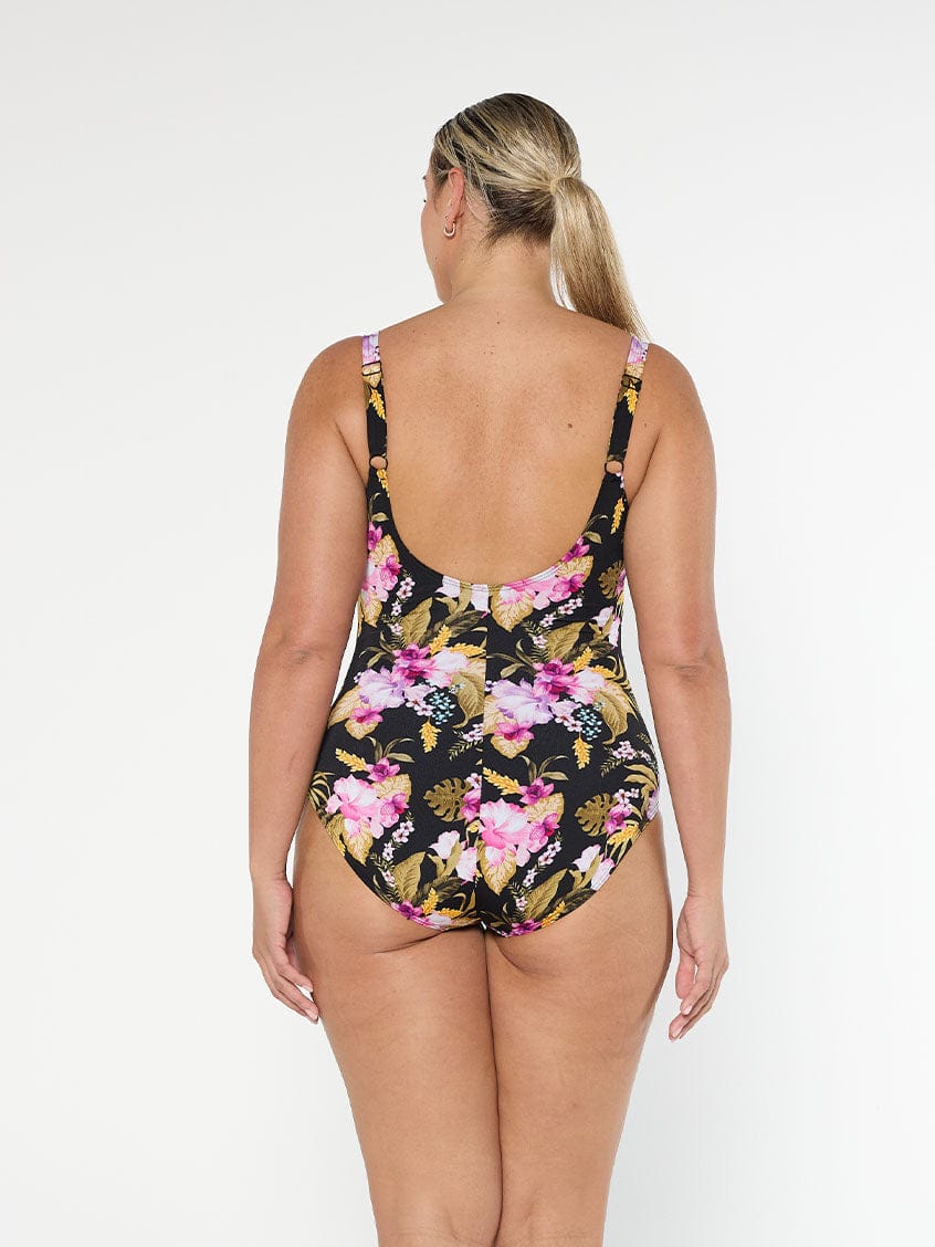Blonde model wears low scoop back one piece with pink and gold floral chlorine resistant fabric with adjustable straps