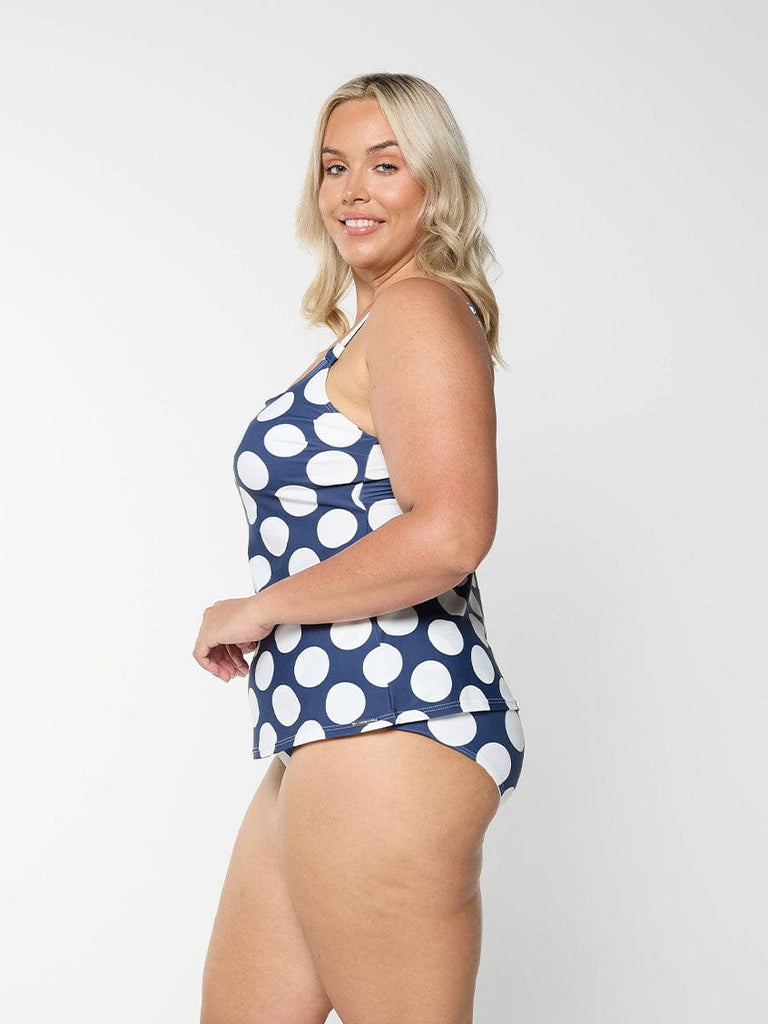 Blonde model showing the side of a flattering tankini top for women in navy and large polkadot pattern