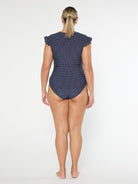 Woman wearing a navy polka dot swimsuit on a white background