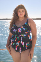 Model wearing black with bright florals 3 tier tankini and matching pant on boat