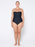 Woman wearing a black strapless swimsuit on a white background
