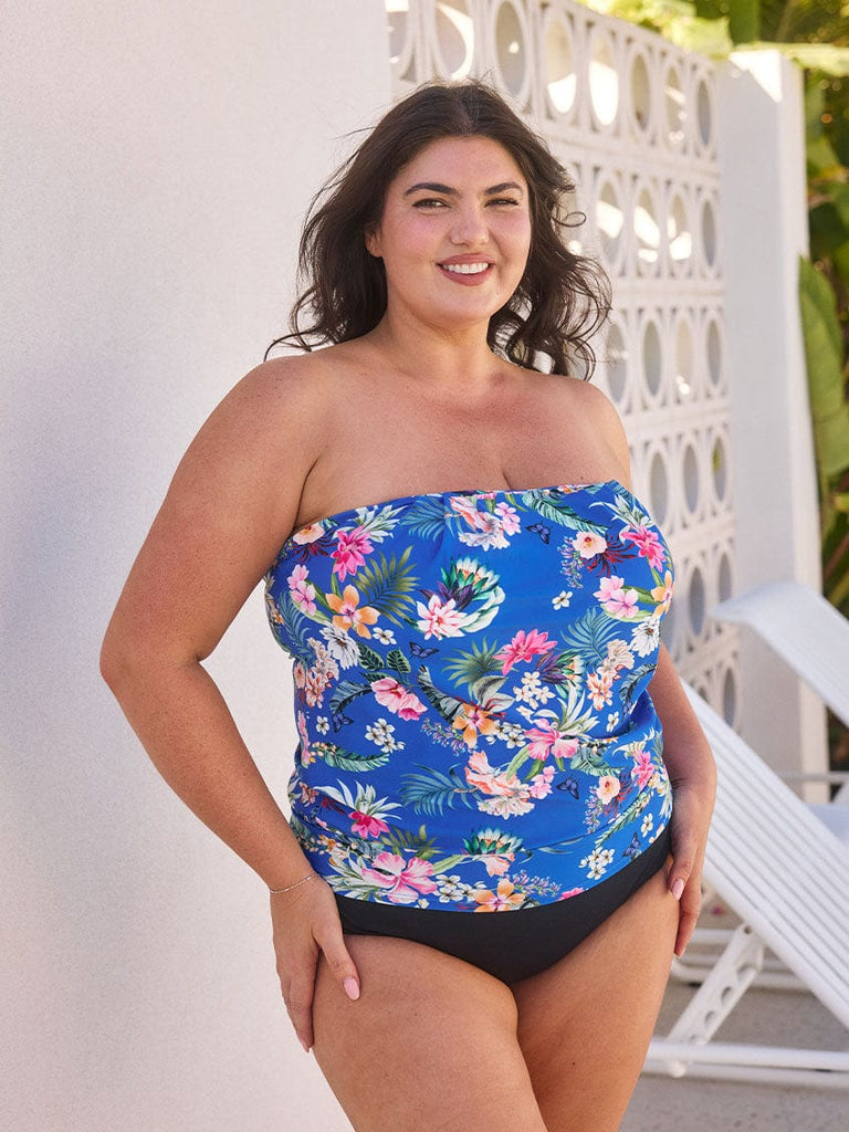 Brunette model wears bandeau tankini top with the straps removed in a vibrant blue floral print