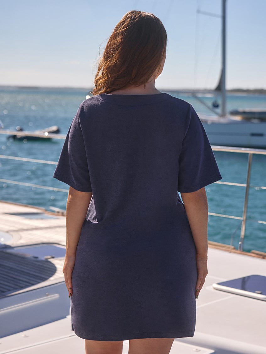 Woman wearing a navy blue dress on a boat with water and sky in the background
