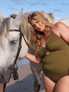 Blonde model wears stunning olive green cutout swimsuit with adjustable halter neck