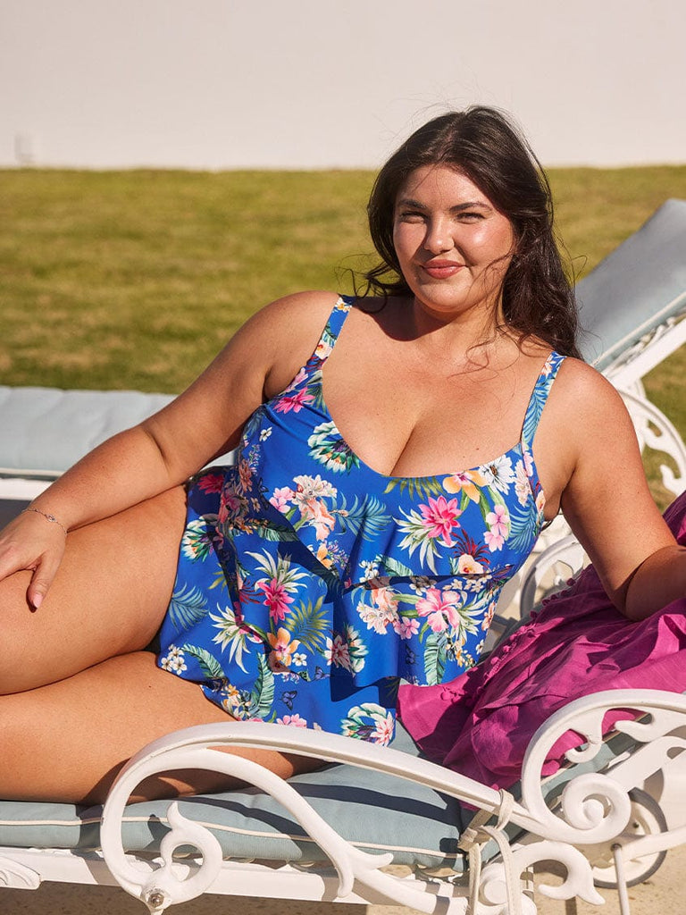 Brunette model wears flattering blue floral one piece with shelf bra and 3 tier design for tummy control