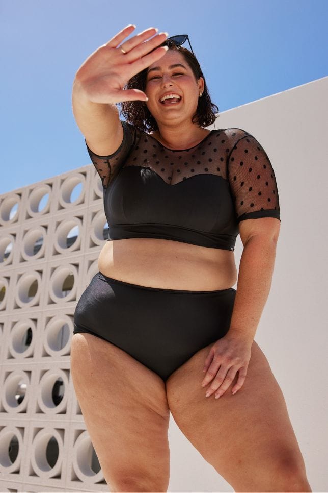 dark haired model wearing a retro sweetheart crop bikini top with a black high waisted pant