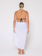 Woman wearing a black strapless top and white striped towel on a plain background