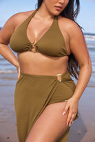 Woman wearing a green bikini and sarong on a beach