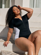 Model sitting down wearing a chlorine resistant short sleeve one piece with textured print