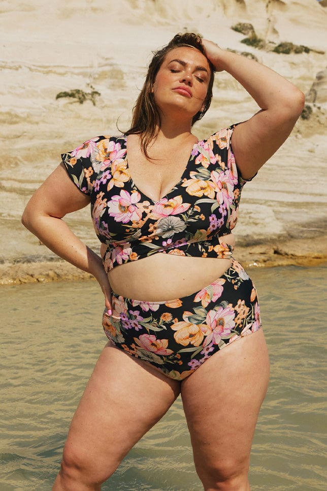 Brunette model wearing black floral bikini botoms