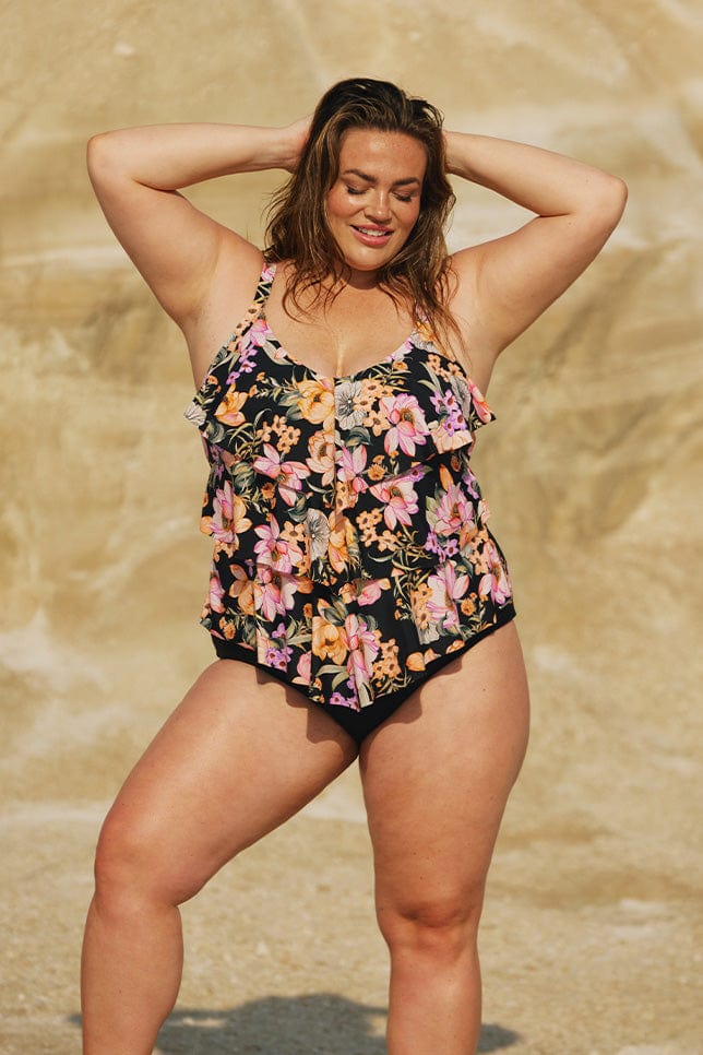 Brunette model wears black and pink floral swim tankini top
