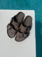Brown sandals with black buckles on a diving board over pool