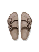 Pair of beige sandals with double buckles on a white background