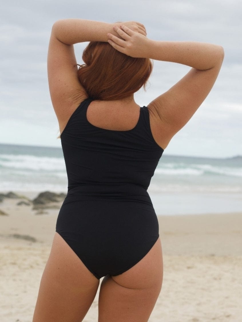 Person wearing a black high back swimsuit on a beach