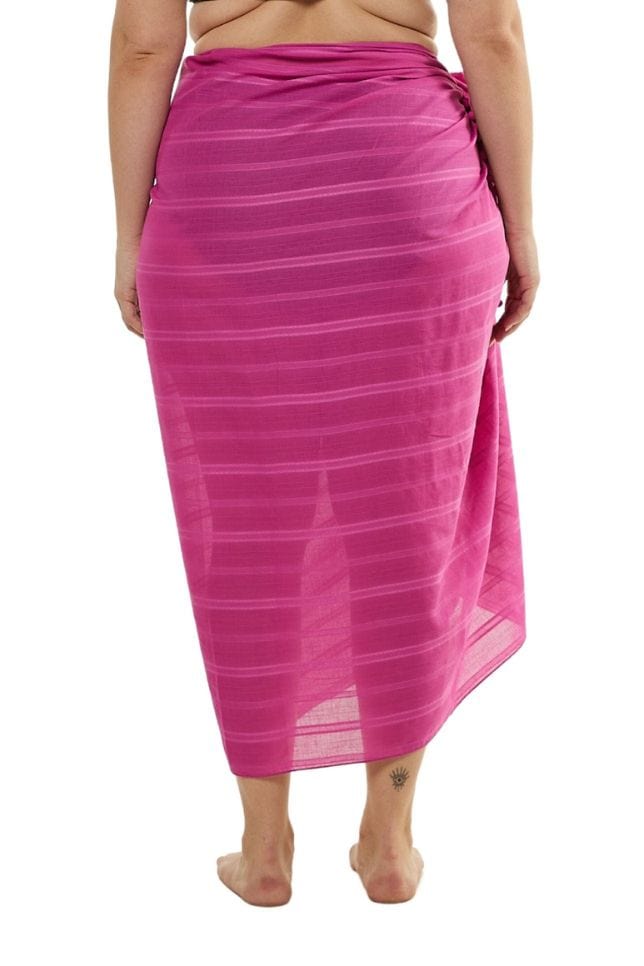 Model wearing flattering long pink sarong skirt with pom pom detail