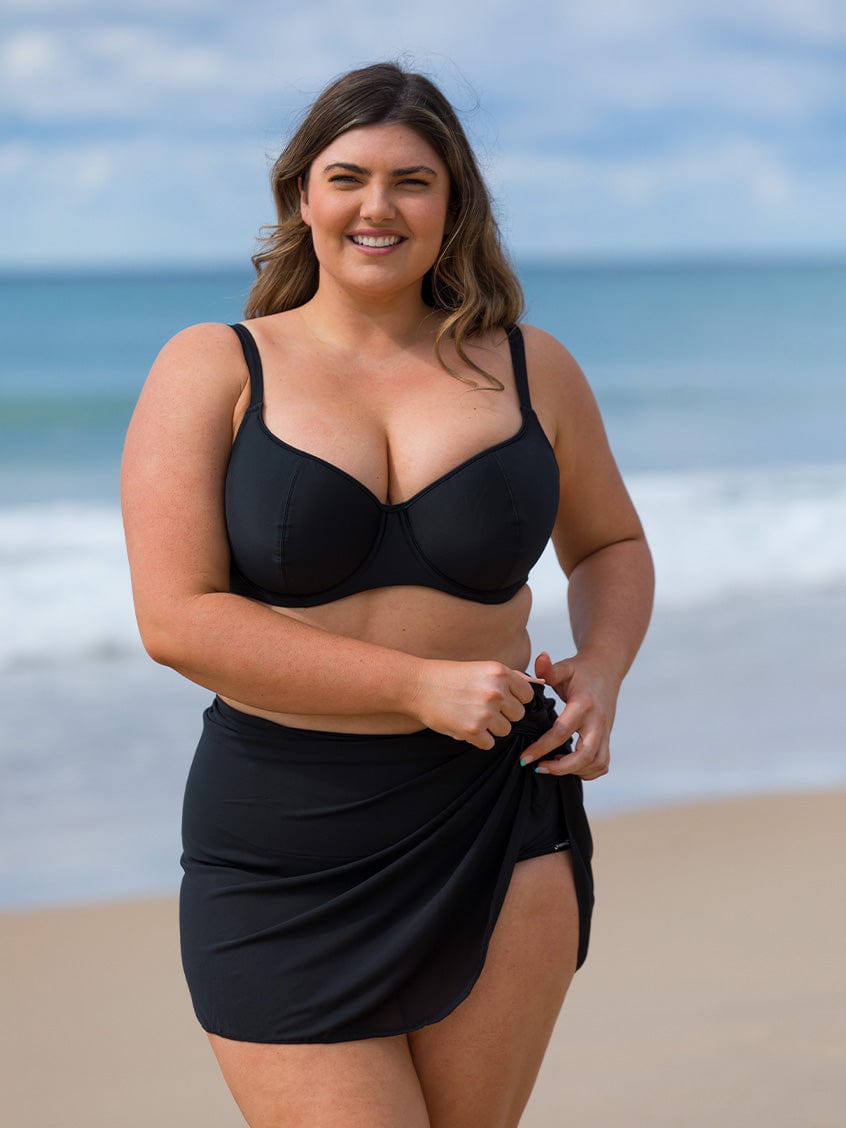 model wearing black mesh skirt with black bikini on beach