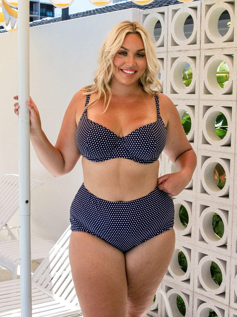 model wearing navy polka dot high waist swim bottom
