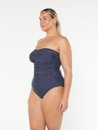 model showing side of navy polka dot strapless swimsuit