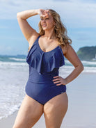 model wearing navy and white dots long frill one piece at beach