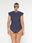 model showing full coverage back of navy polka dot frill sleeve swimsuit