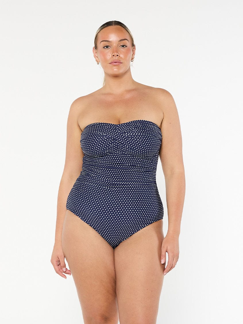 model wearing navy and white dots strapless one piece
