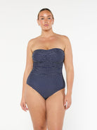 model wearing navy and white dots strapless one piece
