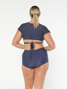 model showing tie back of navy polka dot wrap bikini top