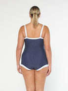 model showing back of navy polka dot boyleg one piece