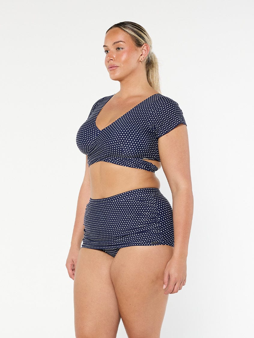model showing side of navy polka dot wrap bikini top