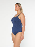 model showing side of navy polka dot women's swimsuit