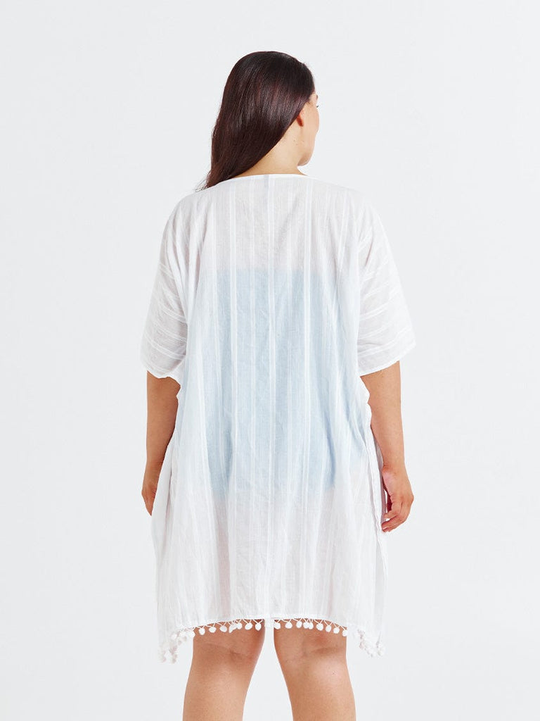 Woman facing back wearing a short sleeve kaftan dress in white cotton with pompom detail