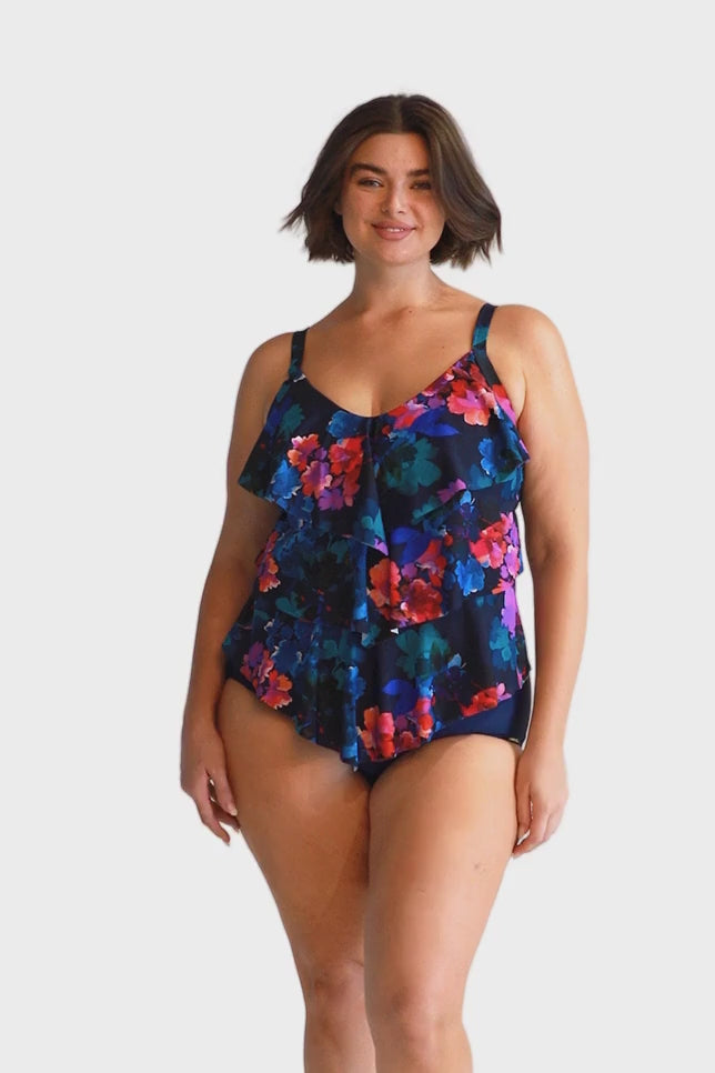 brunette model wears navy blue and pink floral ruffle tankini top