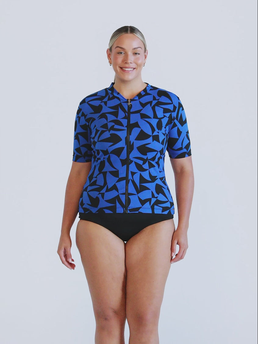 Model in studio wearing short sleeve rash vest in royal blue and black print