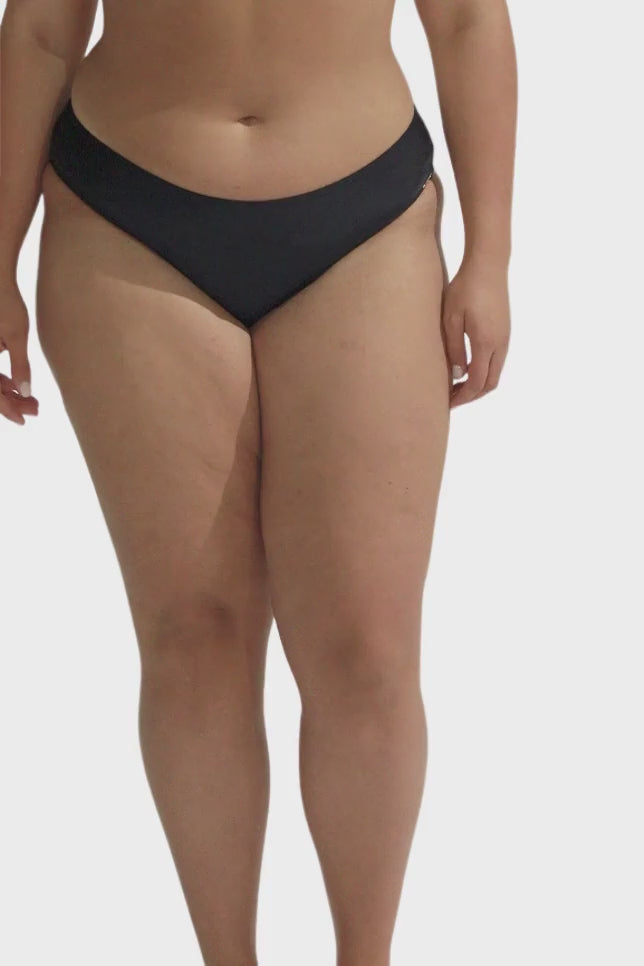 model wearing black low rise bikini bottoms