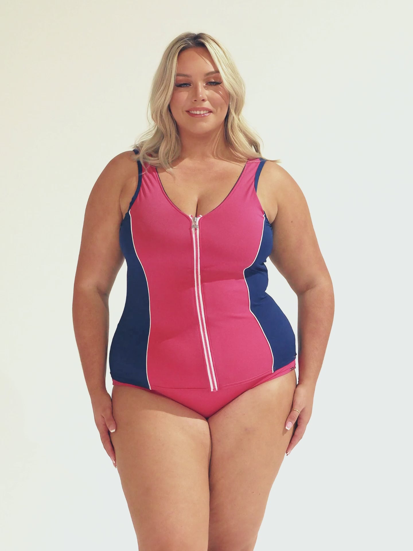 Model wearing navy and pink zip up tankini with matching pink bottoms
