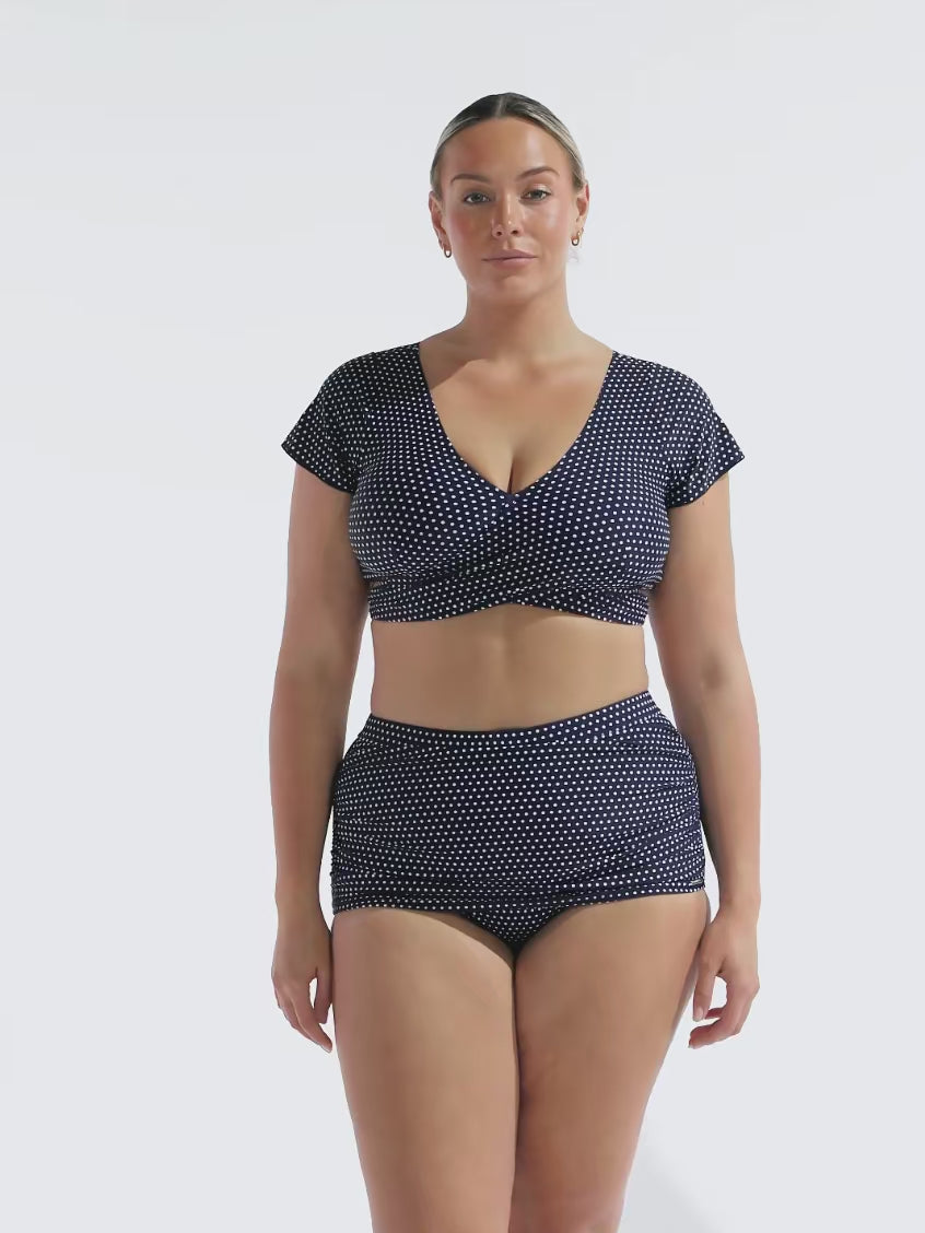 model wearing navy polka dot wrap bikini top with matching skirted bottoms