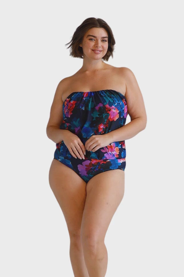 Brunette model wears navy floral flouncy one piece swimsuit