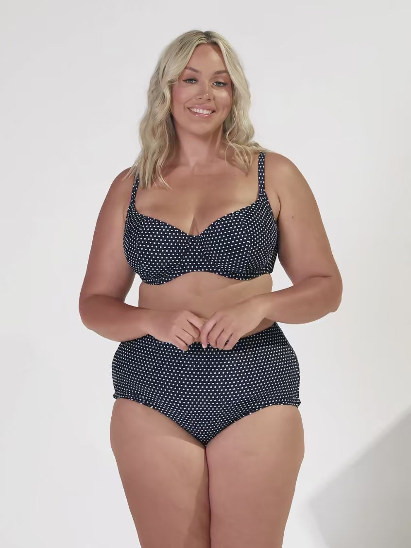 model wearing navy and white dots high waisted bikini bottom with matching top
