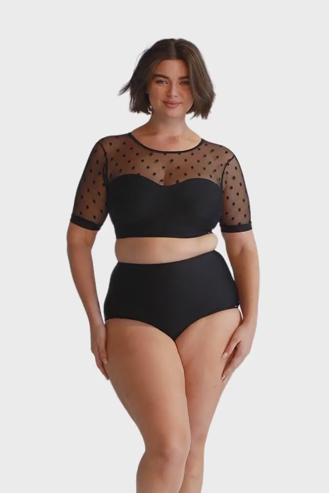 Brunette model wearing black mesh polka dot crop bikini top