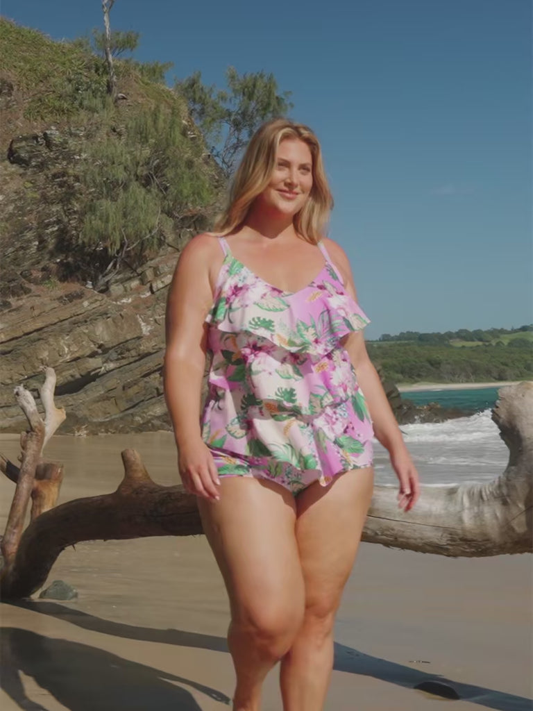 model wearing pink floral layered tankini on beach