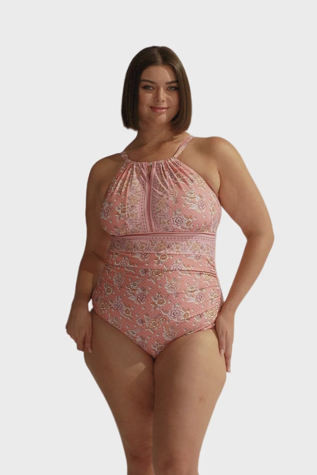 Brunette model wearing pink floral full coverage swimsuit