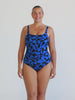 Blonde model in studio wearing tank one piece in chlorine resistant blue and black print