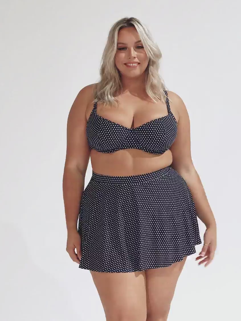 model wearing navy polka dot skater skirt with underwire bikini top
