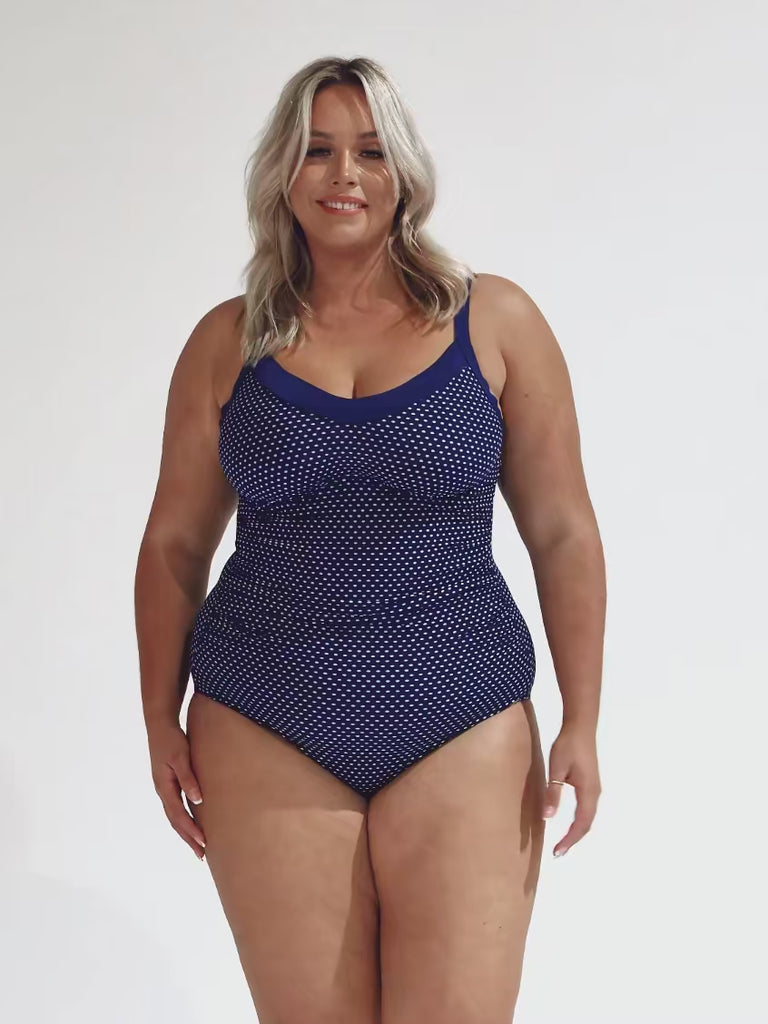 model wearing navy polka dot underwire one piece swimsuit